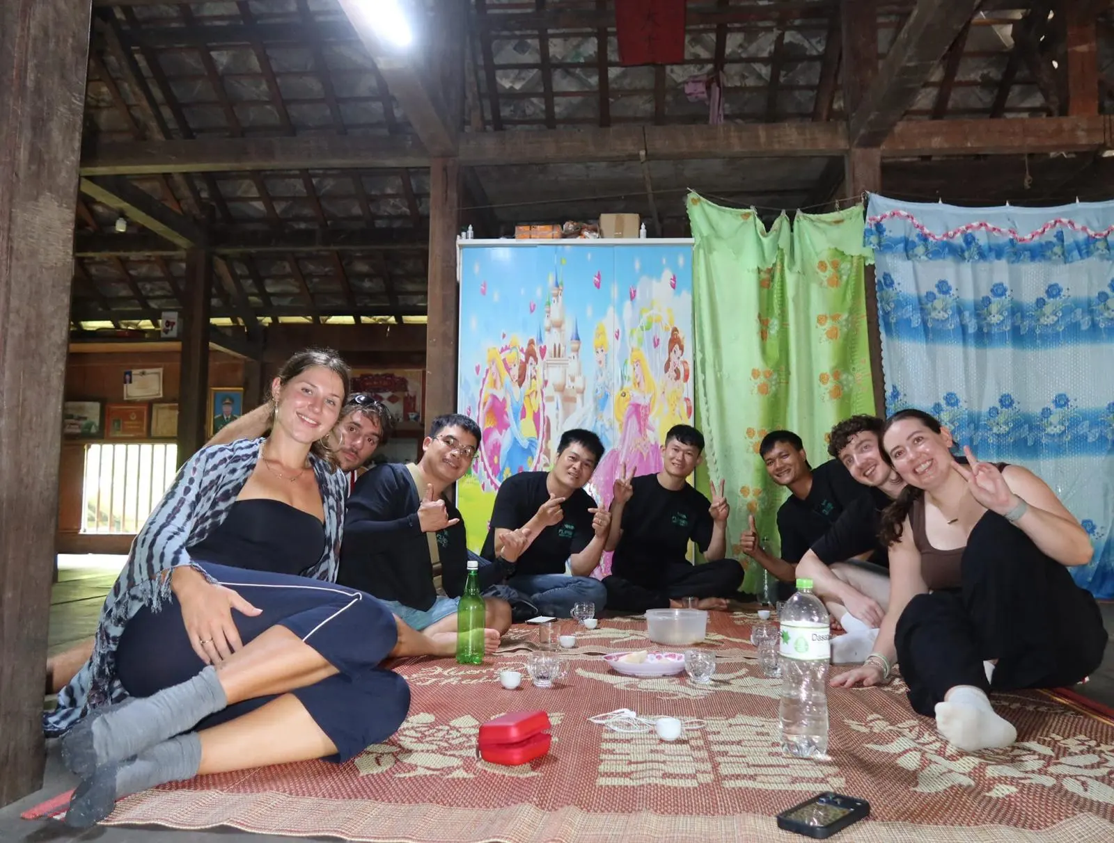 Guests and guides sitting on the mat inside a homestay, drinks between them