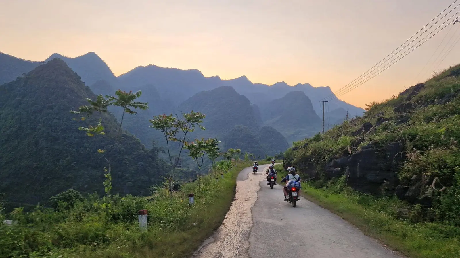 Riders strung out along a quiet road with the hills going blue at sunset